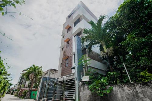 Talamban Viejo的住宿－Cornerstone Manor Inn，一座高大的建筑,前面有一棵棕榈树