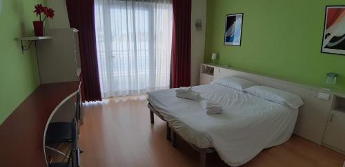 una camera con letto bianco in una stanza verde di Hotel Lago Losetta a Sestriere