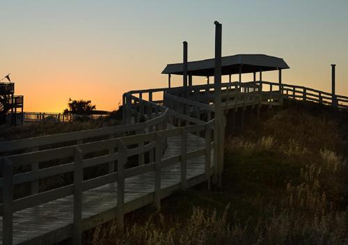 a wooden boardwalk on the beach at sunset at Atlantic Beach Resort, a Ramada by Wyndham in Atlantic Beach