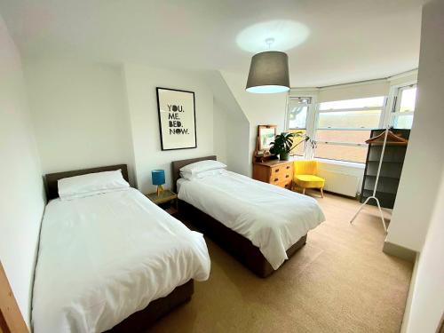a bedroom with two beds and a window at Upper Rooms Seaford in Seaford