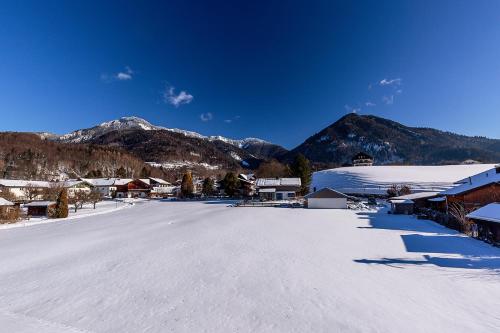 a snow covered street with mountains in the background at Chiemgauferienwohnungen - Maier in Unterwössen