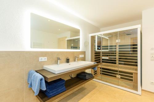 a bathroom with a sink and a large mirror at Chiemgauferienwohnungen - Maier in Unterwössen