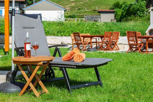 a table and chair with a bottle of wine and a glass at Chiemgauferienwohnungen - Maier in Unterwössen