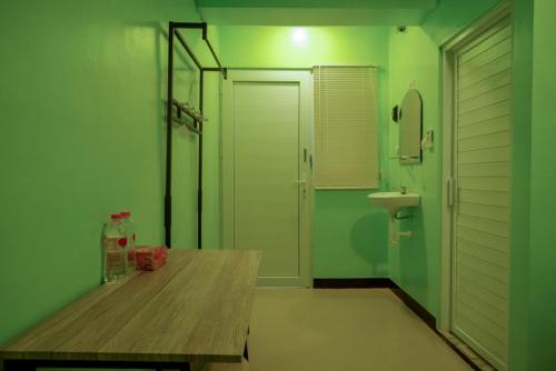 uma casa de banho verde com uma mesa de madeira e um lavatório em RedDoorz @ Jalan Gatot Subroto Semarang em Kalibanteng-kidul