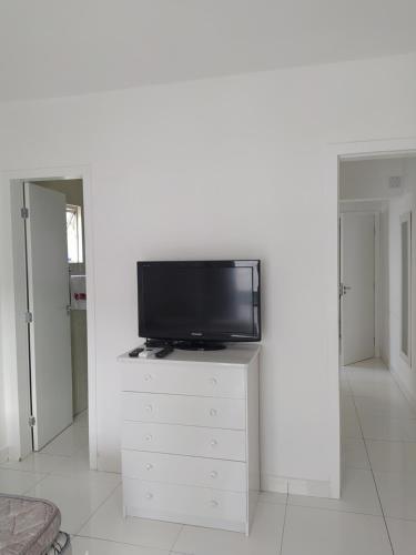 TV de pantalla plana en la parte superior de una cómoda blanca en Apartamento no centro - 2, en Balneário Camboriú