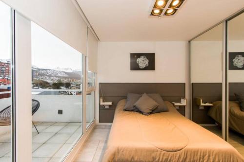 a bedroom with a large bed with glass walls at Temporales Ushuaia - Bahia loft in Ushuaia