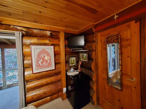 a hallway of a log cabin with a television and a door at Shambhala Bed and Breakfast in Buckhorn