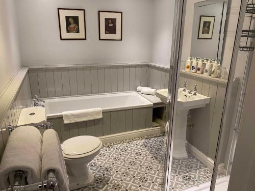 a bathroom with a tub and a toilet and a sink at The Bull Inn in Woodbridge