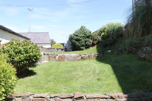 un jardín con una pared de piedra y un patio en The Granary en Swansea