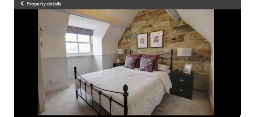 a bedroom with a bed and a stone wall at Carlton Cottage, Castleton in Castleton
