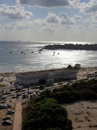 a beach with parked cars and boats in the water at Acre sea view 11th floor apartment in ‘Akko