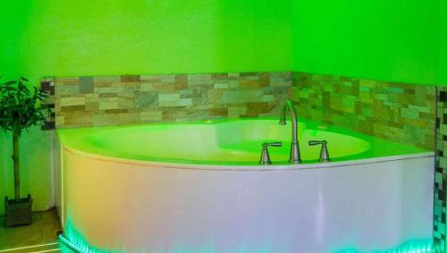 a bath tub in a green room with a sink at Magnuson Hotel Little Rock South in Little Rock