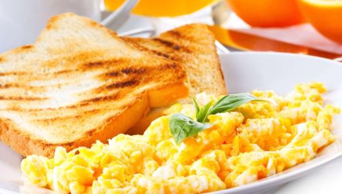 a plate of scrambled eggs with toast and orange juice at Magnuson Extended Stay and Suites Airport Hotel in Irving