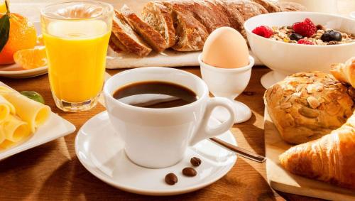a table with a cup of coffee and a plate of breakfast foods at Magnuson Extended Stay and Suites Airport Hotel in Irving