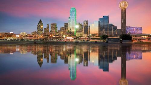 a city skyline at night with a reflection in the water at Magnuson Extended Stay and Suites Airport Hotel in Irving
