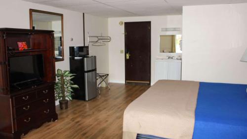a bedroom with a bed and a dresser with a television at Colonial Inn Ellsworth in Ellsworth