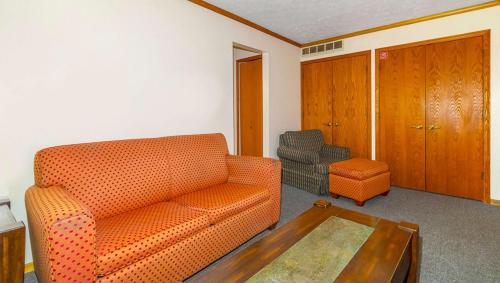 a living room with an orange couch and a coffee table at Magnuson Hotel Extended Stay Canton Ohio in Lake Cable