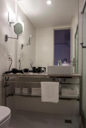 a white bathroom with a sink and a mirror at H Niteroi Hotel in Niterói