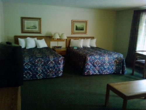 a hotel room with two beds and a table at Will Rogers Inn in Claremore