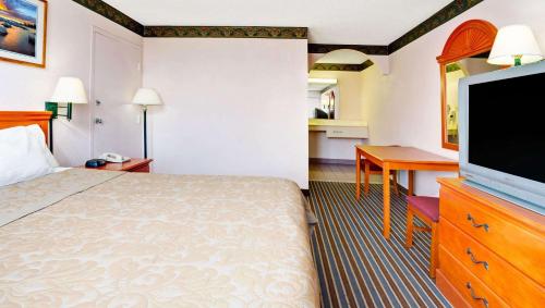 a hotel room with a bed and a flat screen tv at Magnuson Hotel Jacksonville Downtown in Jacksonville