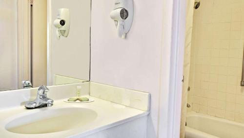 a white bathroom with a sink and a mirror at Magnuson Hotel Jacksonville Downtown in Jacksonville