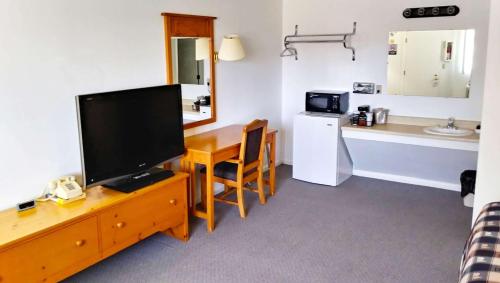 a living room with a television and a table and a kitchen at Drop Tyne Lodge in Franklin