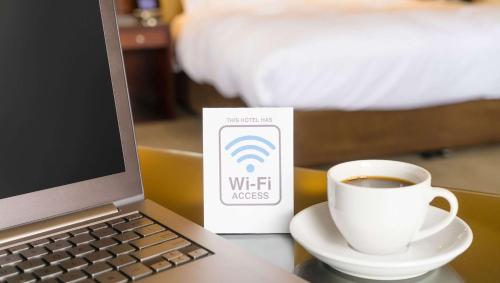 a laptop computer and a cup of coffee on a table at Golden Wheat Budget Host Inn Junction City in Junction City