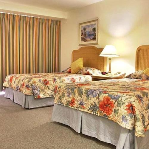 a hotel room with two beds and a lamp at Castaways Resort and Suites in Freeport