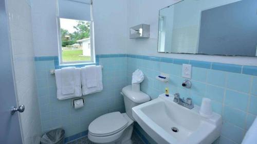 uma casa de banho em azulejos azuis com um WC e um lavatório em Sun Plaza Motel em Silver Springs