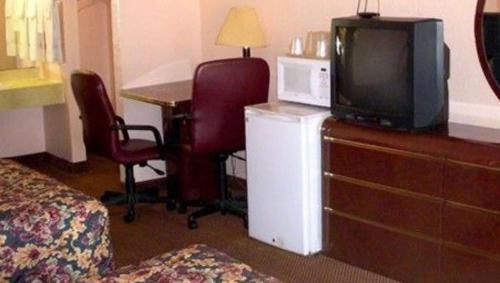 Habitación de hotel con TV en un tocador con escritorio y mesa. en Executive Royal Inn Clewiston, en Clewiston