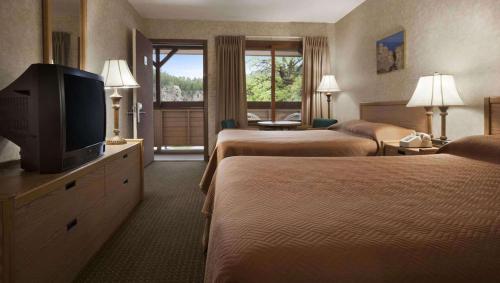 a hotel room with two beds and a flat screen tv at Magnuson Grand Rushmore View in Keystone