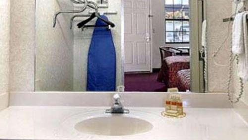 a bathroom with a sink and a blue dress in the mirror at Gray Inn & Suites in Gray
