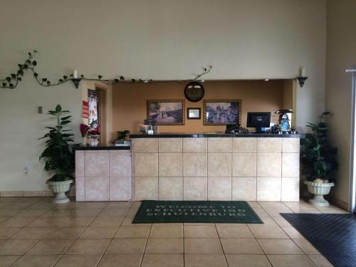 a restaurant with a counter in a room with plants at Executive Inn Schulenburg in Schulenburg
