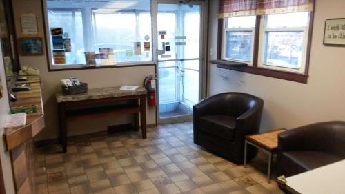 a waiting room with a chair and a desk and windows at Mayflower Motel Milford in Milford