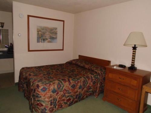 a hotel room with a bed and a lamp and a dresser at Arrowhead Inn New Salem in New Salem