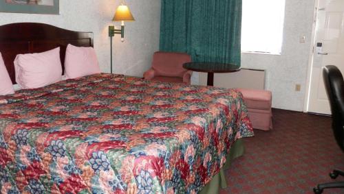 a hotel room with a bed and a chair at Magnuson Hotel Fowlerville in Fowlerville
