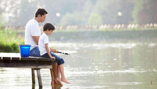 a man and a boy sitting on a dock fishing at Motel Forrest Rockville in Rockville