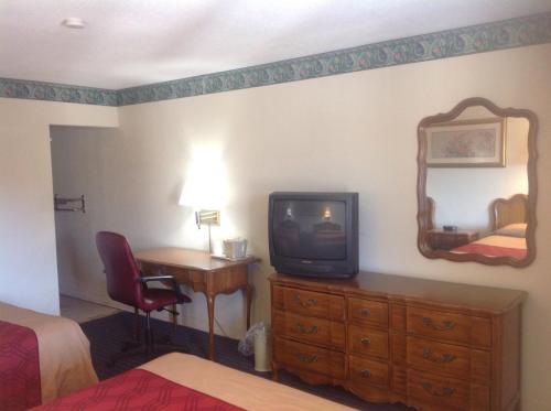 a hotel room with a tv and a desk with a mirror at New Haven Inn in New Haven