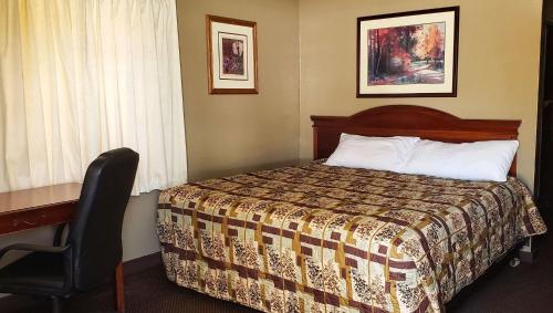 a bedroom with a bed and a desk and a chair at Windmill Inn Lynden in Lynden
