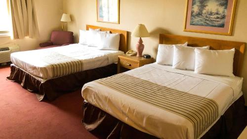 une chambre d'hôtel avec deux lits et une chaise dans l'établissement Magnuson Hotel Dixon, à Dixon