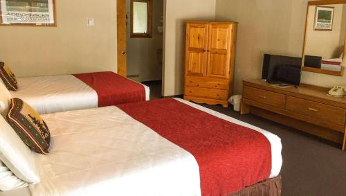 a hotel room with two beds and a television at Adirondack Lodge Old Forge in Old Forge