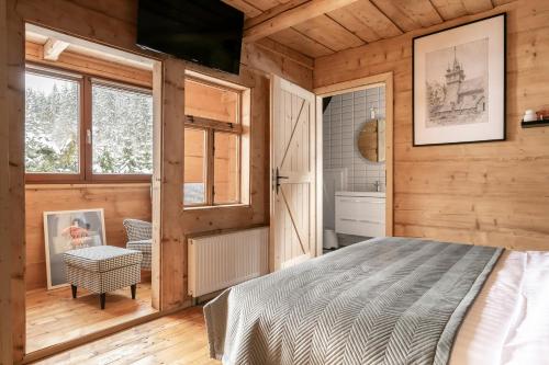 a bedroom with a bed in a room with wooden walls at APARTAMENTY DVOOR1924 in Poronin