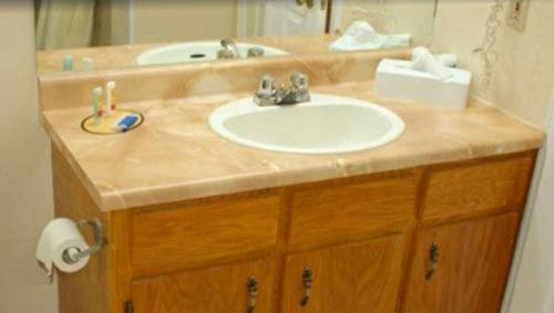 a bathroom counter with a sink and a mirror at Traveller's Inn Prince Edward Island in Summerside