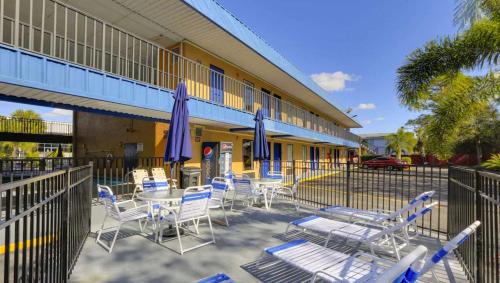 a group of chairs and tables with umbrellas in front of a building at Magnuson Hotel Bradenton in Bradenton