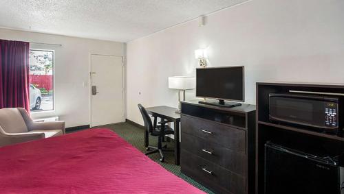 a hotel room with a bed and a desk with a television at Magnuson Hotel Bradenton in Bradenton