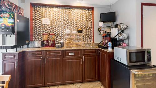 a kitchen with wooden cabinets and a microwave at Magnuson Hotel Bradenton in Bradenton