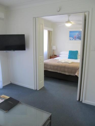 a bedroom with a bed and a flat screen tv at Costa D'Ora Holiday Apartments in Gold Coast
