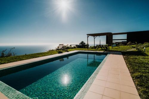 a swimming pool with the ocean in the background at Calheta Glamping Pods - Nature Retreat in Calheta