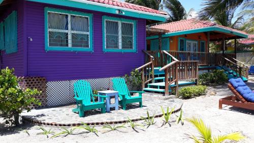 a purple house with chairs and a table on the beach at Coco's Beachfront Cabanas in Seine Bight Village