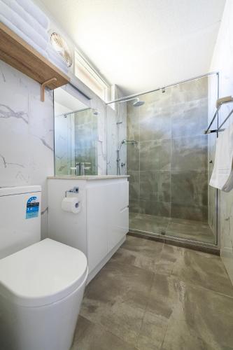 a bathroom with a toilet and a glass shower at The Wurruk Motel in Sale